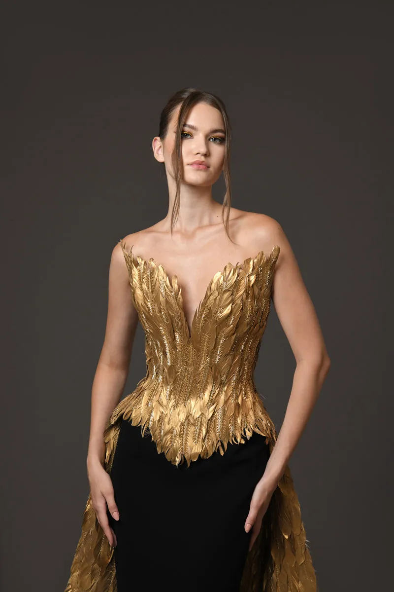 A golden feather corseted bustier with a dramatic overskirt, paired with a silk black crêpe skirt